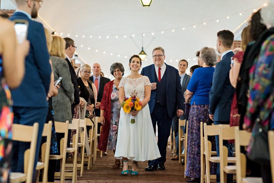 A bride walks down the isle in blue shoes with her parents behind her at a wedding at the Shambles in south Philly.